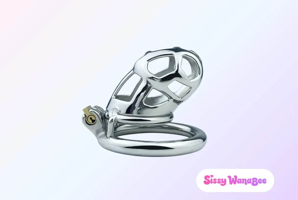 Studio product shot of an FRRK Mamba F3153 chastity cage in polished stainless steel against a soft pink and lavender gradient, the openwork mesh shell curving above a heavy round base ring, a brass lock barrel and keyhole integrated at the front, the editorial seriousness of a second cage chosen after a first