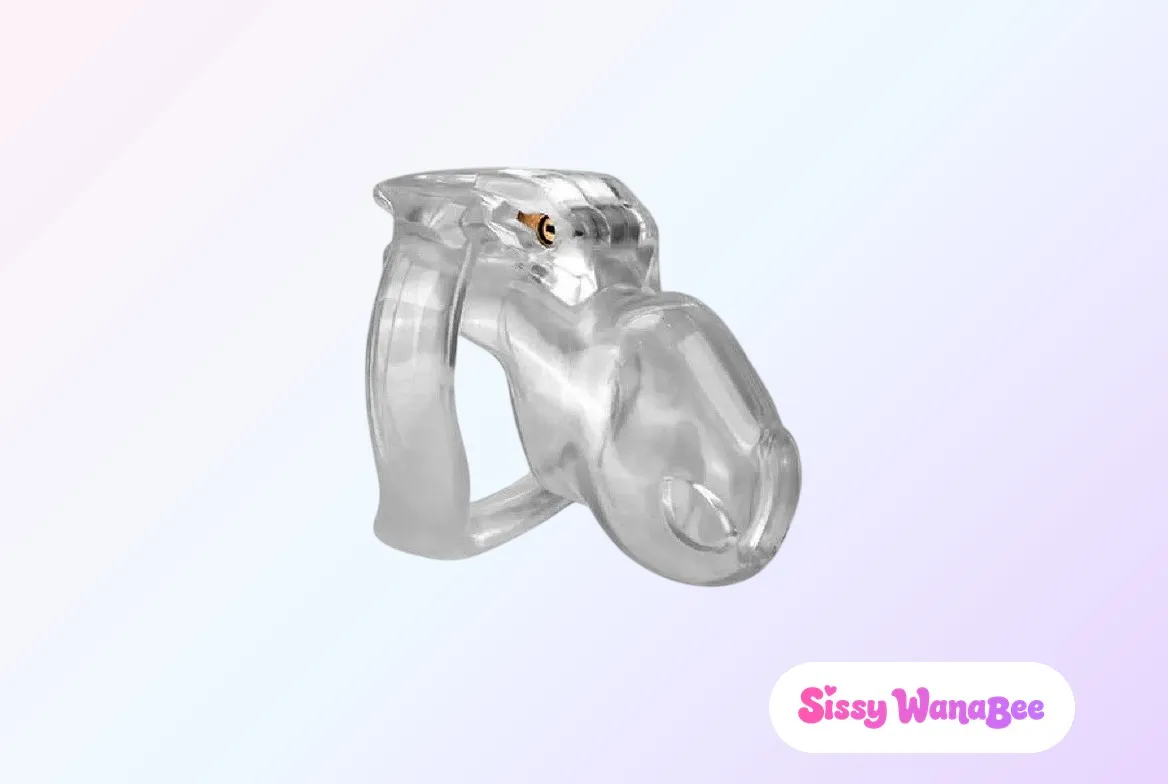 Studio product shot of a Holy Trainer V4 chastity cage in clear resin against a soft pink and lavender gradient, the transparent curved tube and base ring catching the light, a small brass lock pin set into the housing, the quiet domesticity of a sissy's morning ritual