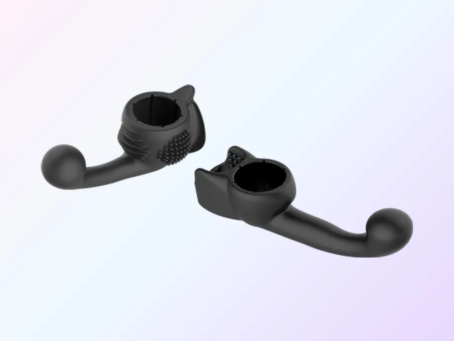The two Lovense Domi 2 attachments in matte black silicone against a soft pink and lavender gradient. On the left the female attachment, a collar carrying a round patch of fine nubs, a row of flexible ribs and a smooth wing, with a firm curved arm ending in a rounded tip. On the right the male attachment, a collar with a nubbed inner pad and an open slot, with its own curved arm and rounded tip.